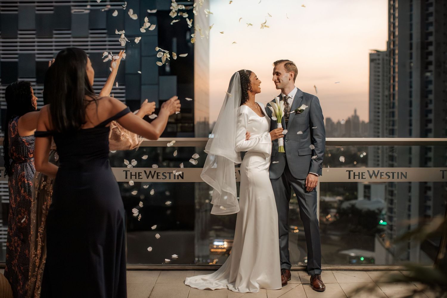 Newlywed couple sharing a moment on rooftop while confetti falls around them.
