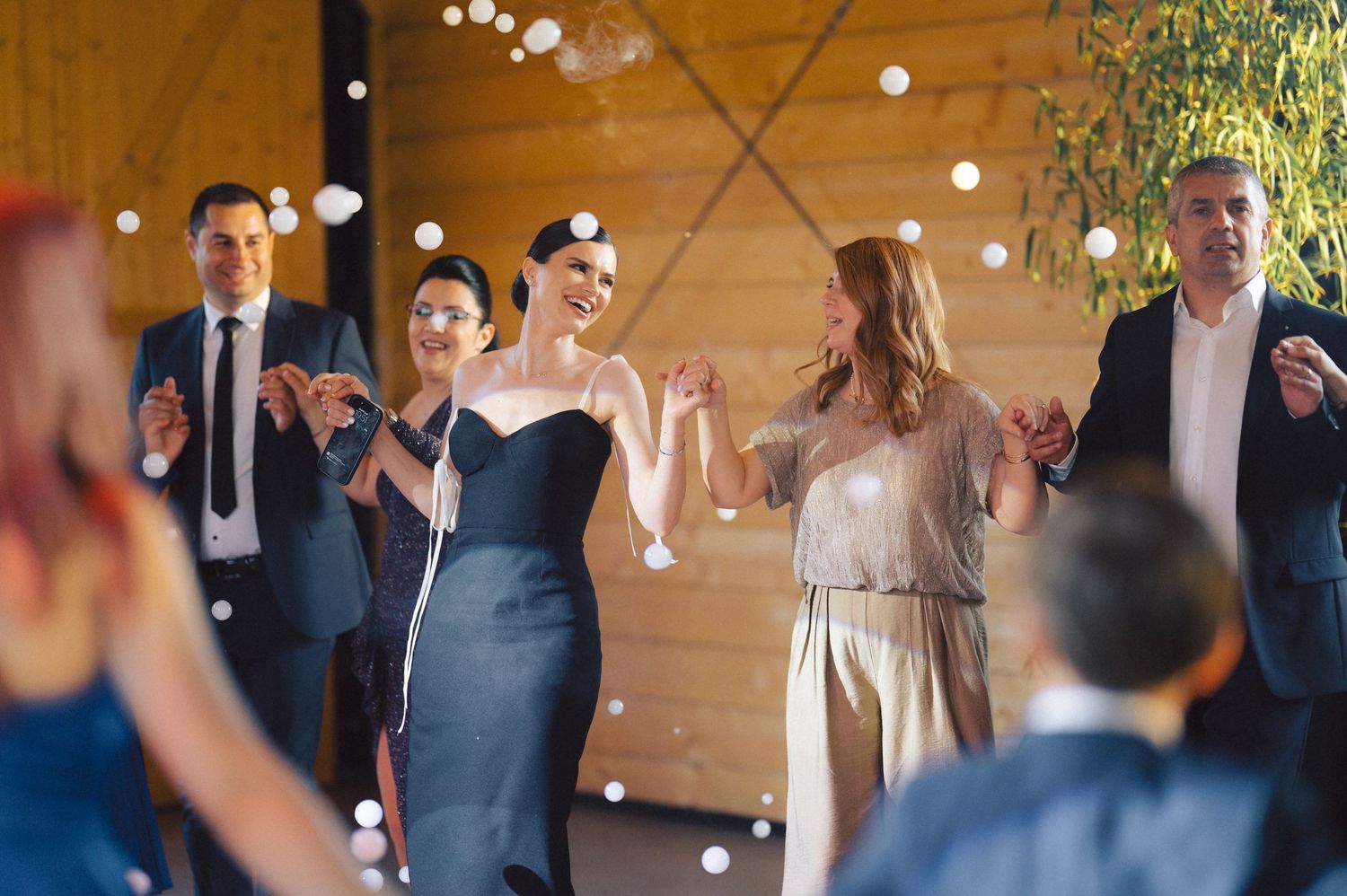 Wedding celebration with guests dancing and throwing bubbles in an elegant indoor venue.
