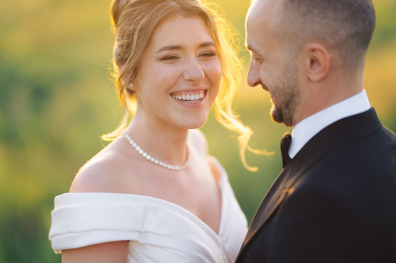 A newlywed couple shares a joyful moment together during golden hour at their outdoor wedding ceremony.