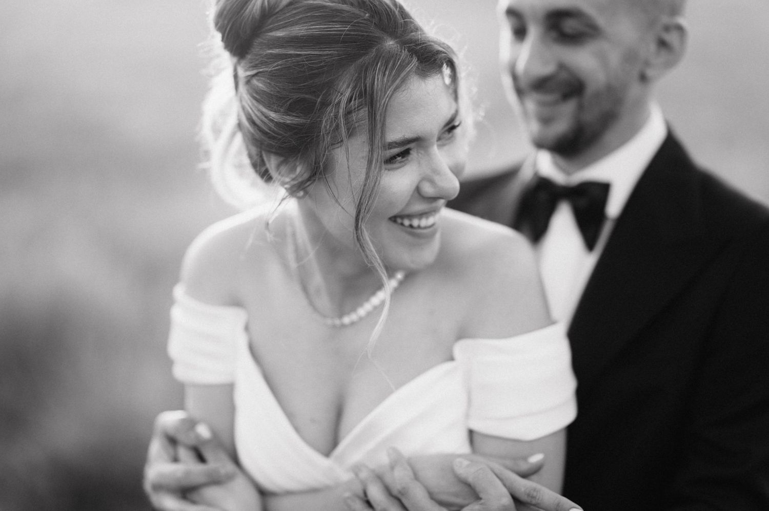 Black and white portrait capturing a joyful moment between a couple in formal attire.