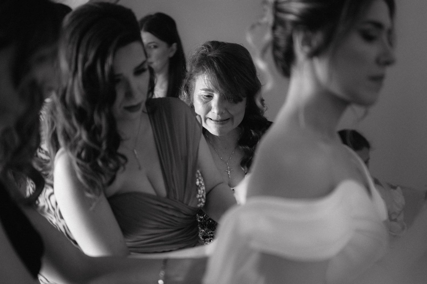 A black and white candid moment of wedding party preparations showing elegantly dressed figures in formal attire.