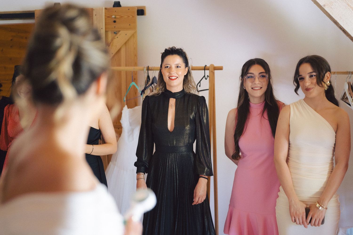 A wedding party in formal attire watches a bride in white, showing a heartfelt moment of preparation and anticipation.