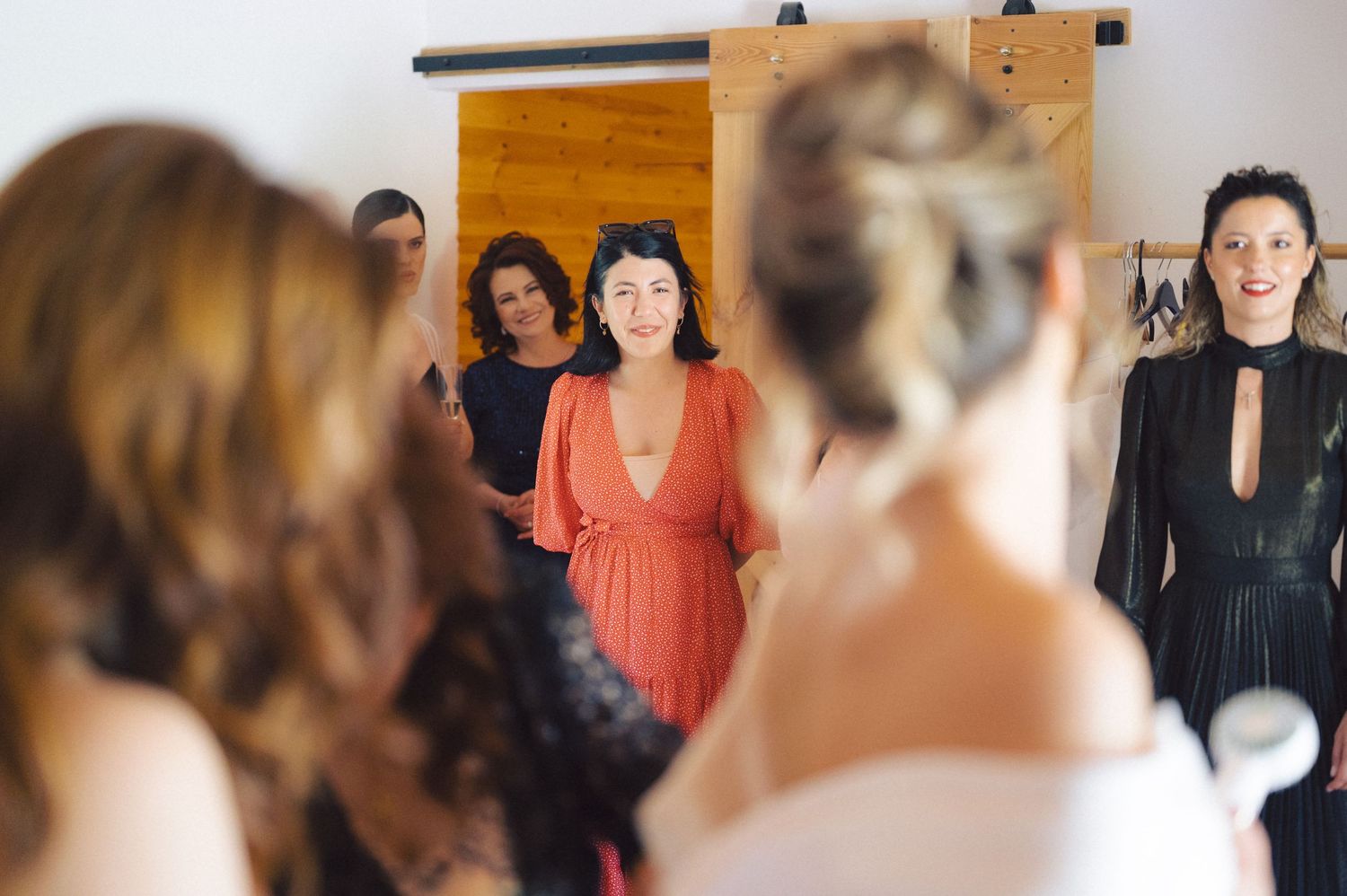A group of people gathered indoors wearing formal attire with a burnt orange wall hanging visible in the background.