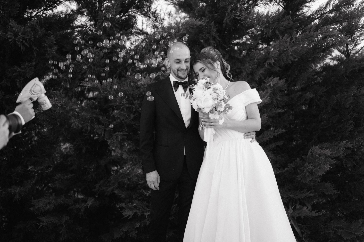 A bride and groom share an intimate moment together outdoors during their black and white wedding photography session.
