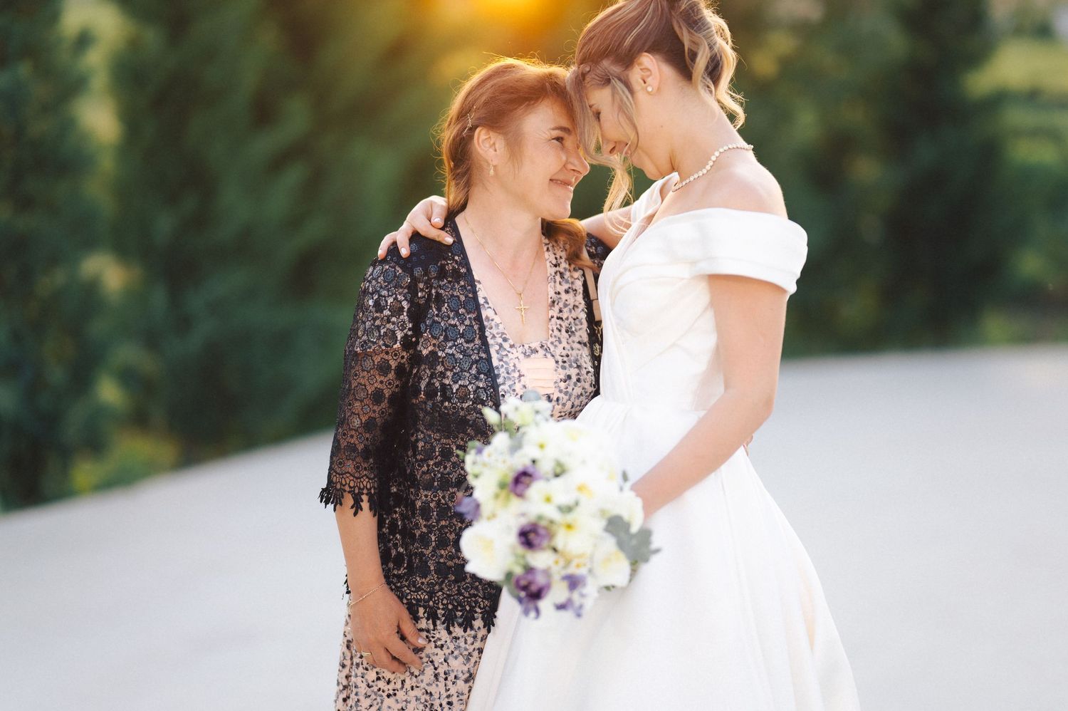 Two people share an intimate moment during a wedding ceremony with sunlit golden hour lighting.