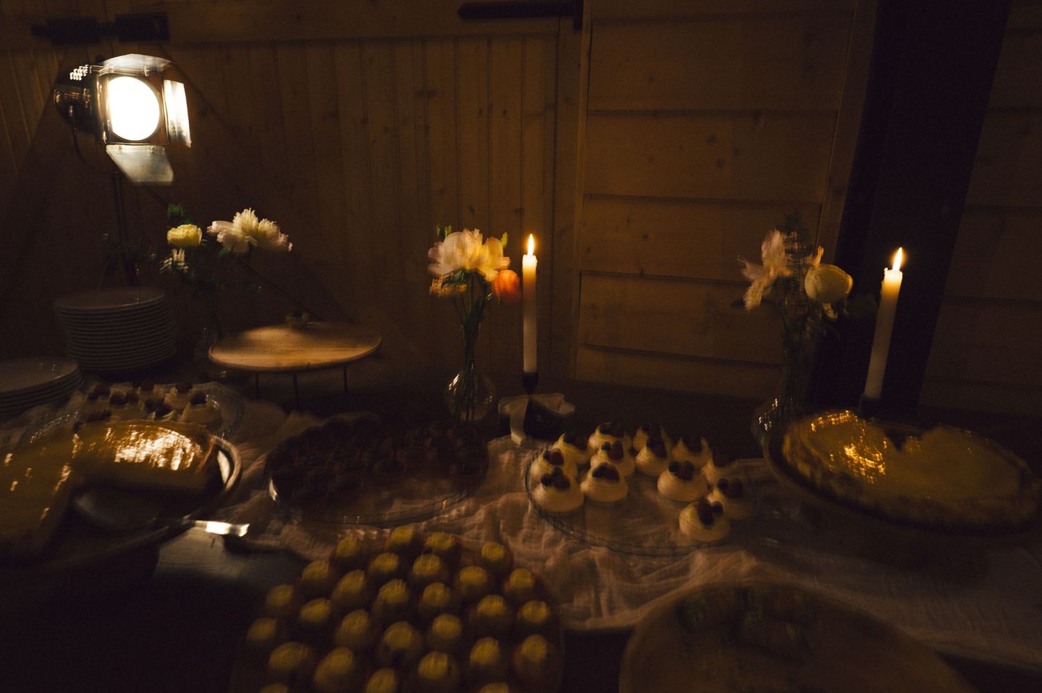 A moody candlelit reception table setup with elegant place settings and floral arrangements.