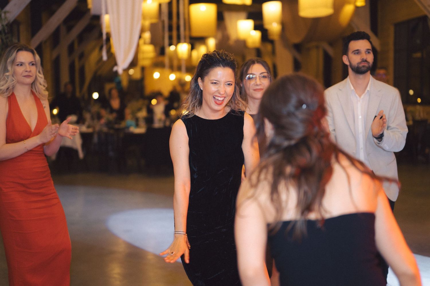 People dancing and celebrating at an elegant indoor event with warm lighting and formal attire.