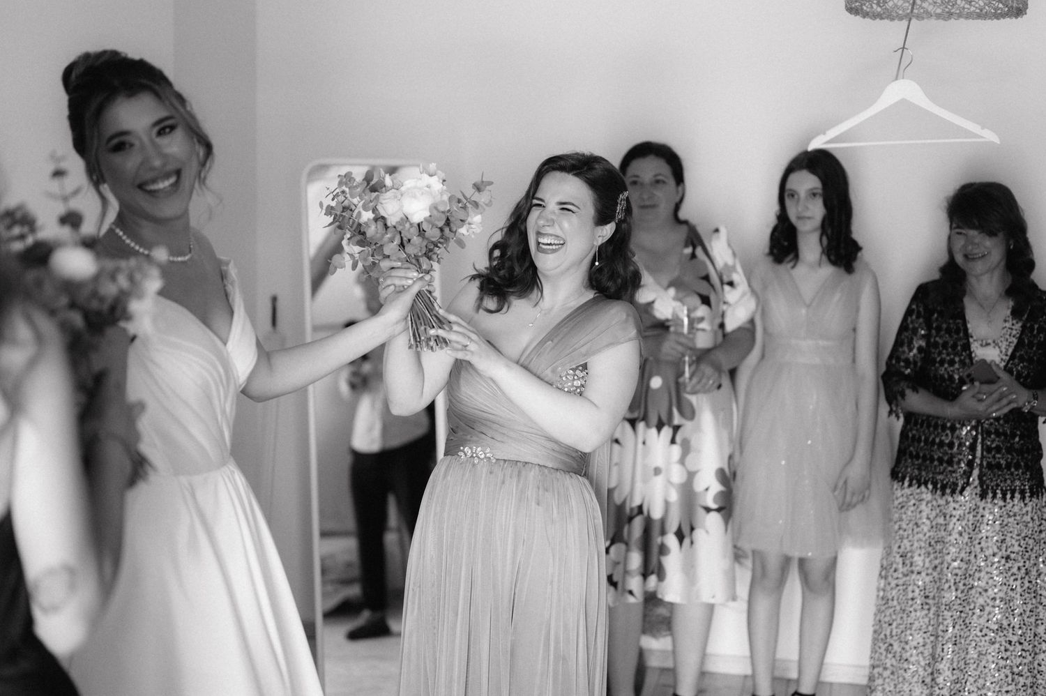 Bridesmaids wearing light-colored dresses share a joyful moment together before the wedding ceremony.