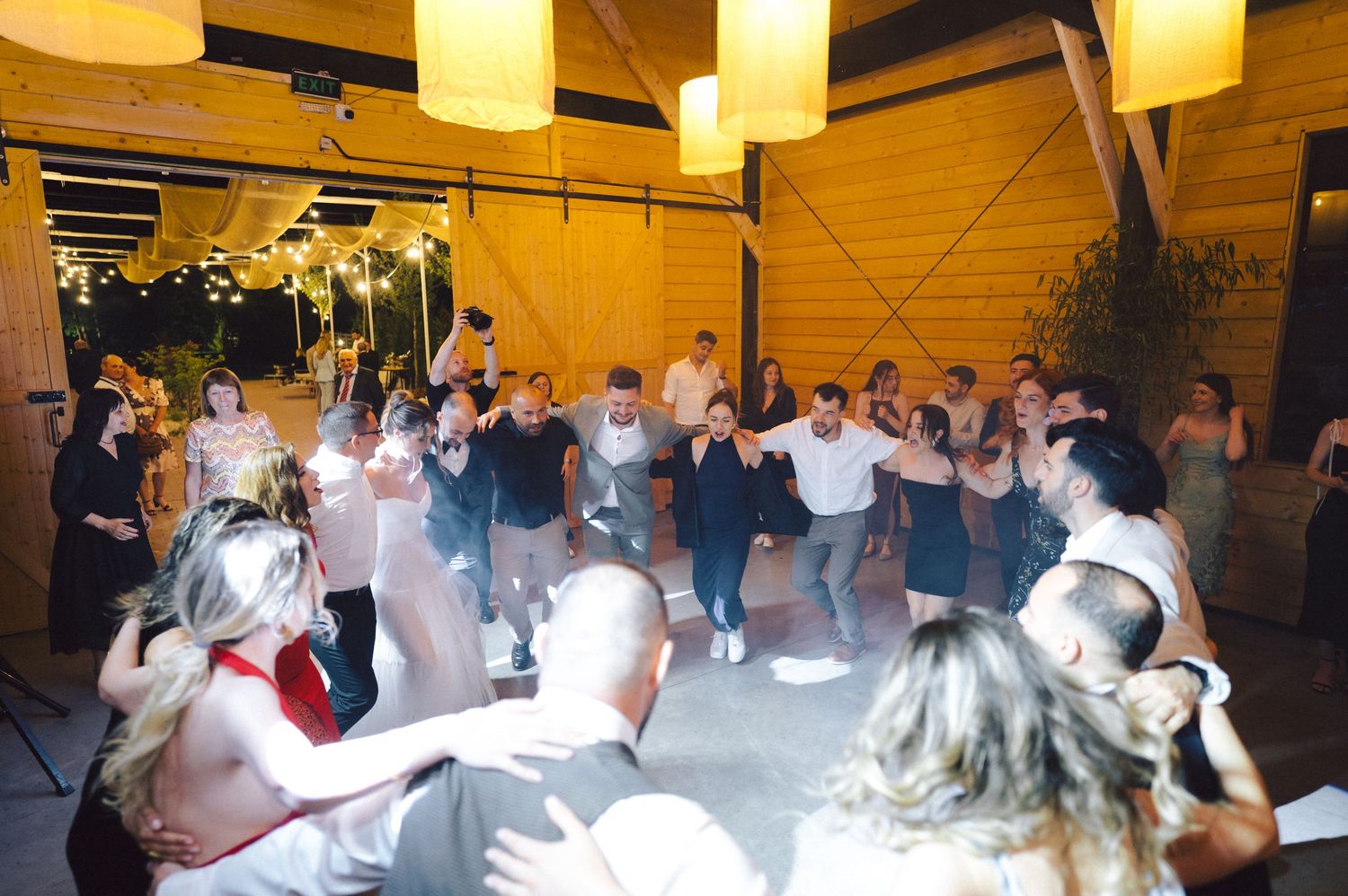 A large crowd of dancers on a wooden dance floor under warm lighting at an indoor venue.