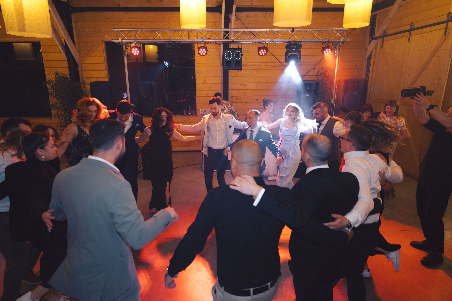 People gathered in a warmly lit room with wood paneled walls dancing and socializing together.