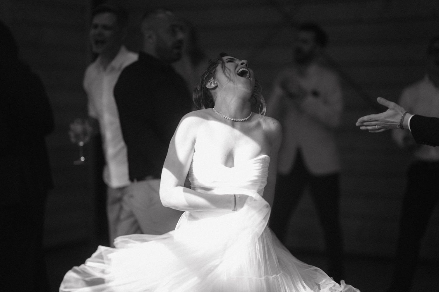 A joyful bride in a white wedding dress spins and laughs on the dance floor at her reception.