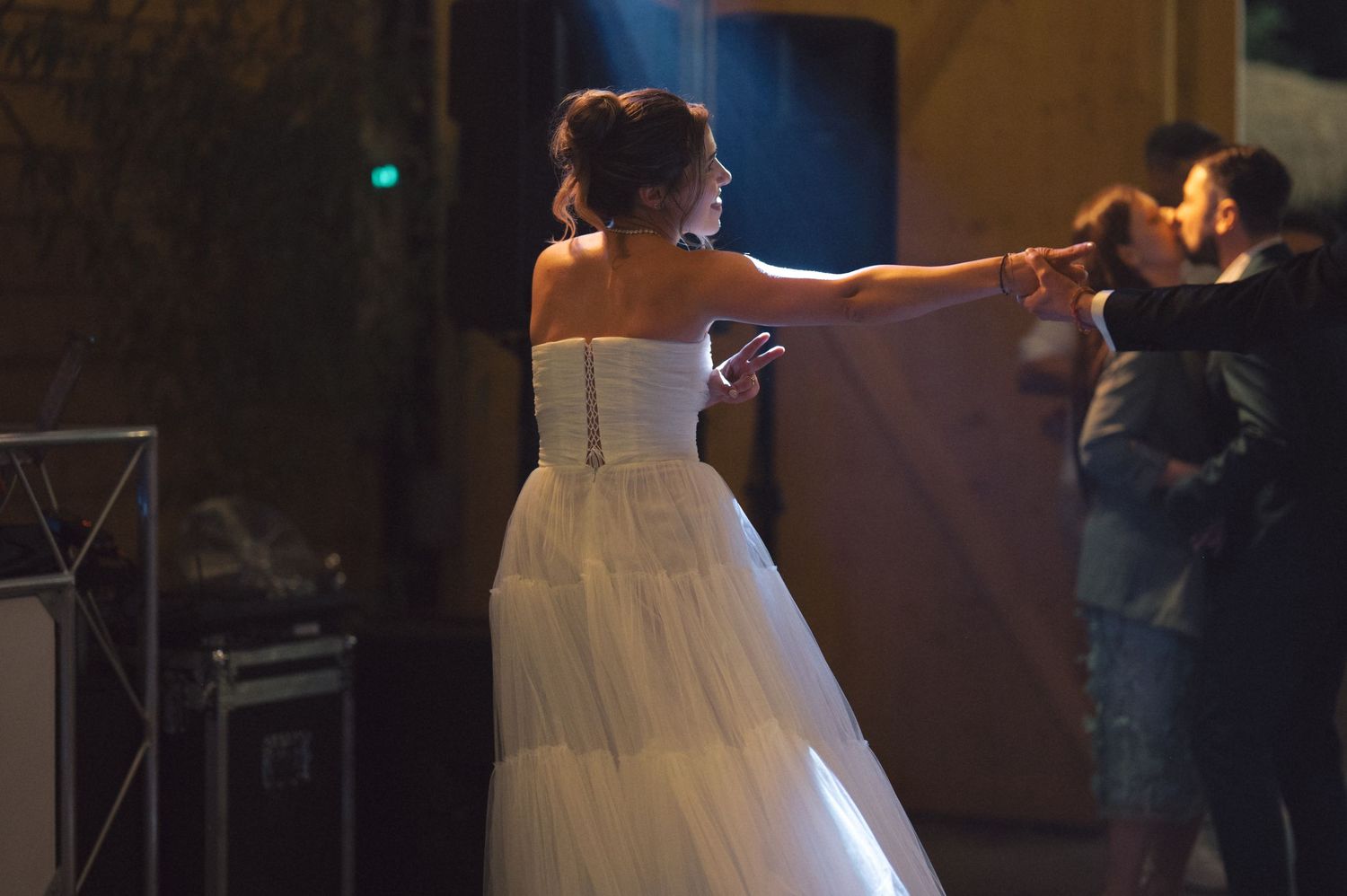 A bride in a flowing white dress dances at a wedding reception under dim lighting.