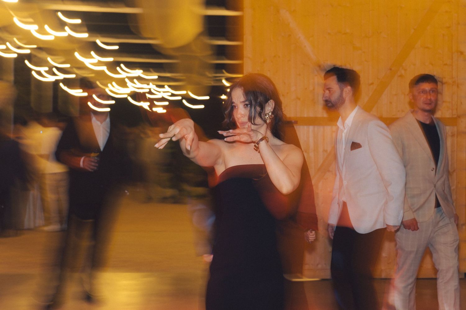 Motion blurred dancers at a formal event with glowing lights creating streaks in the background.