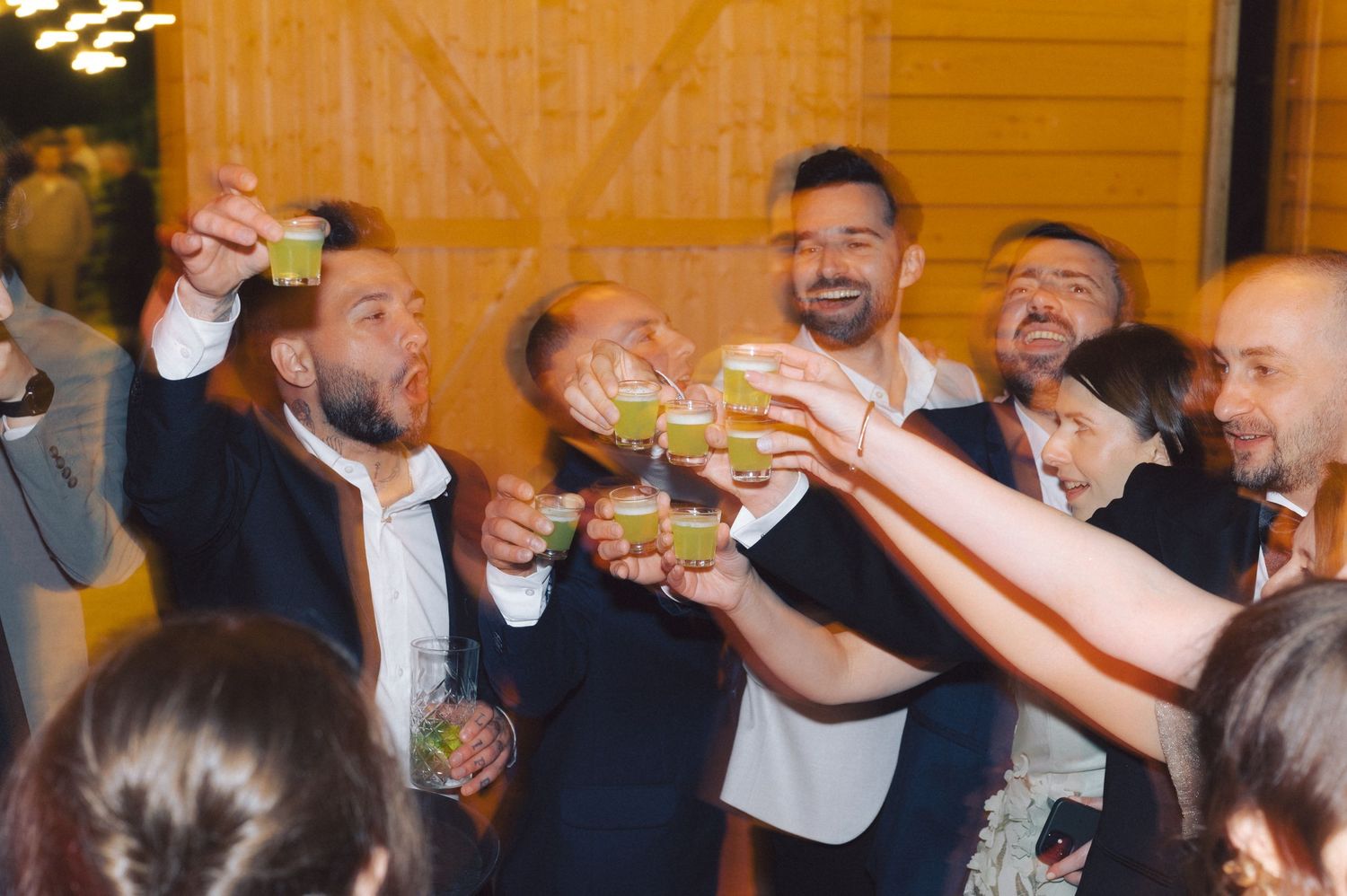A group of people raise their drinks together in a celebratory toast at a festive social gathering.
