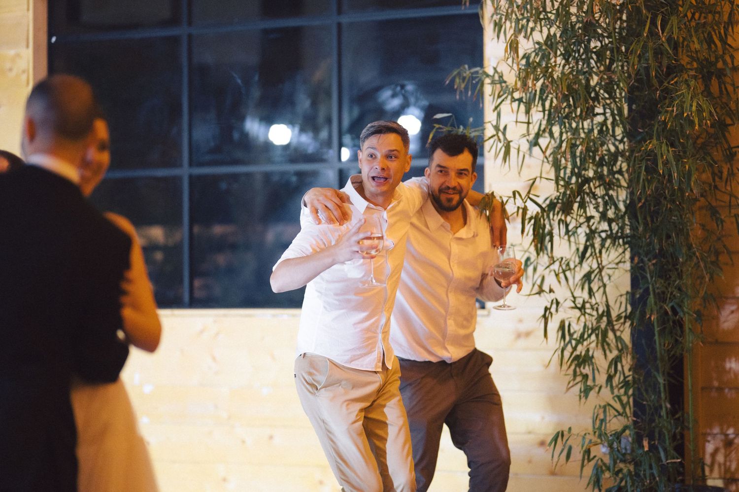 Two people dancing energetically at an evening party with a warm interior lighting atmosphere.