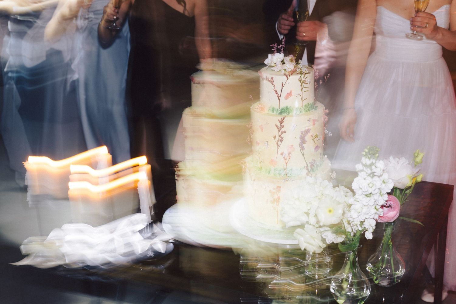A blurred wedding scene with an elegant white cake and candles creating a soft romantic atmosphere at a reception.