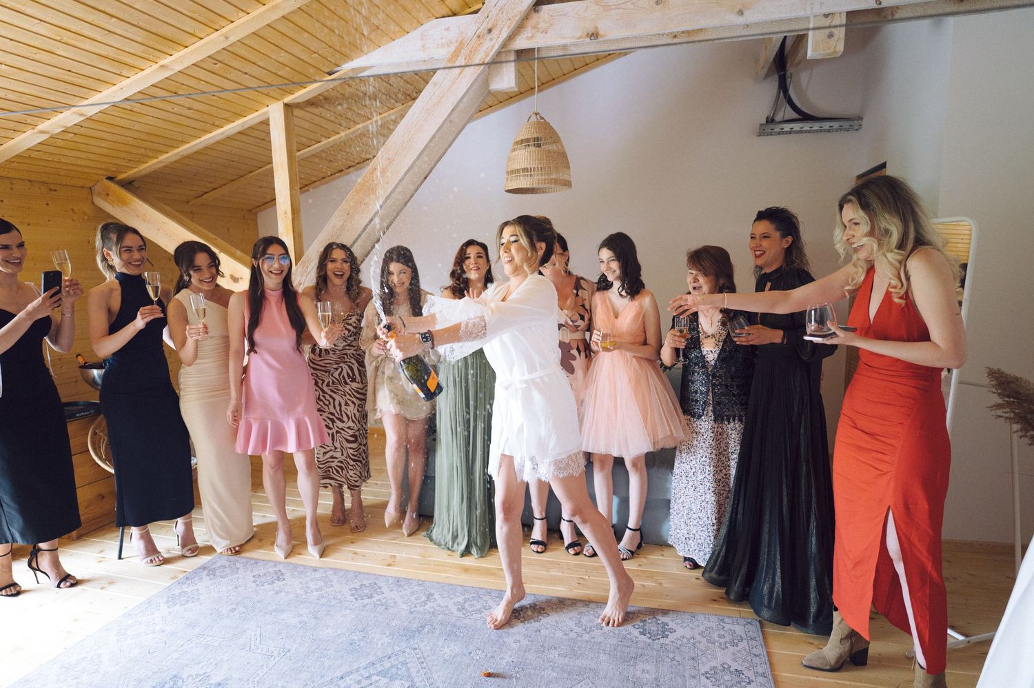 A group of friends in formal dresses standing in a line and dancing together at an indoor celebration.