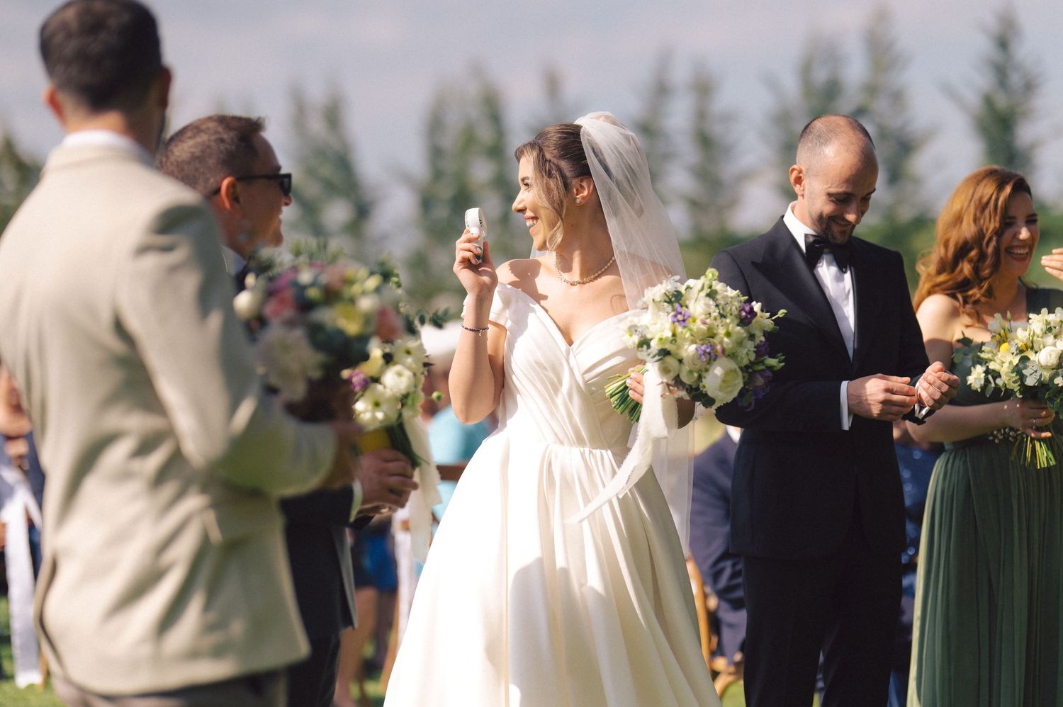 Guests enjoying drinks during an elegant outdoor wedding reception with mountain scenery and floral arrangements.