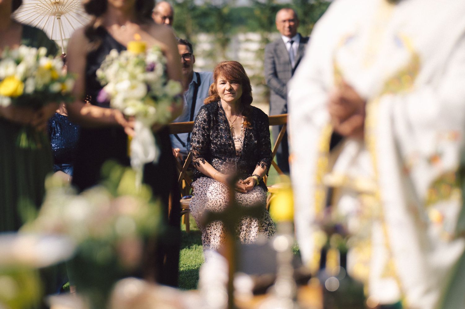 A soft-focus candid moment captured at an outdoor spring event with yellow flowers and people gathered in natural light.