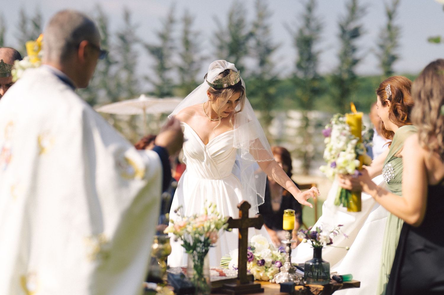 Wedding guests gathered around an outdoor table with flowers and drinks during a reception celebration.