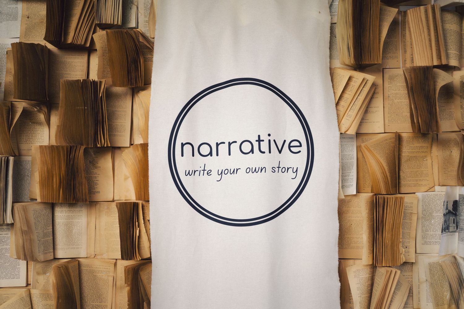 White banner with circular Narrative logo against textured backdrop of stacked brown paper.