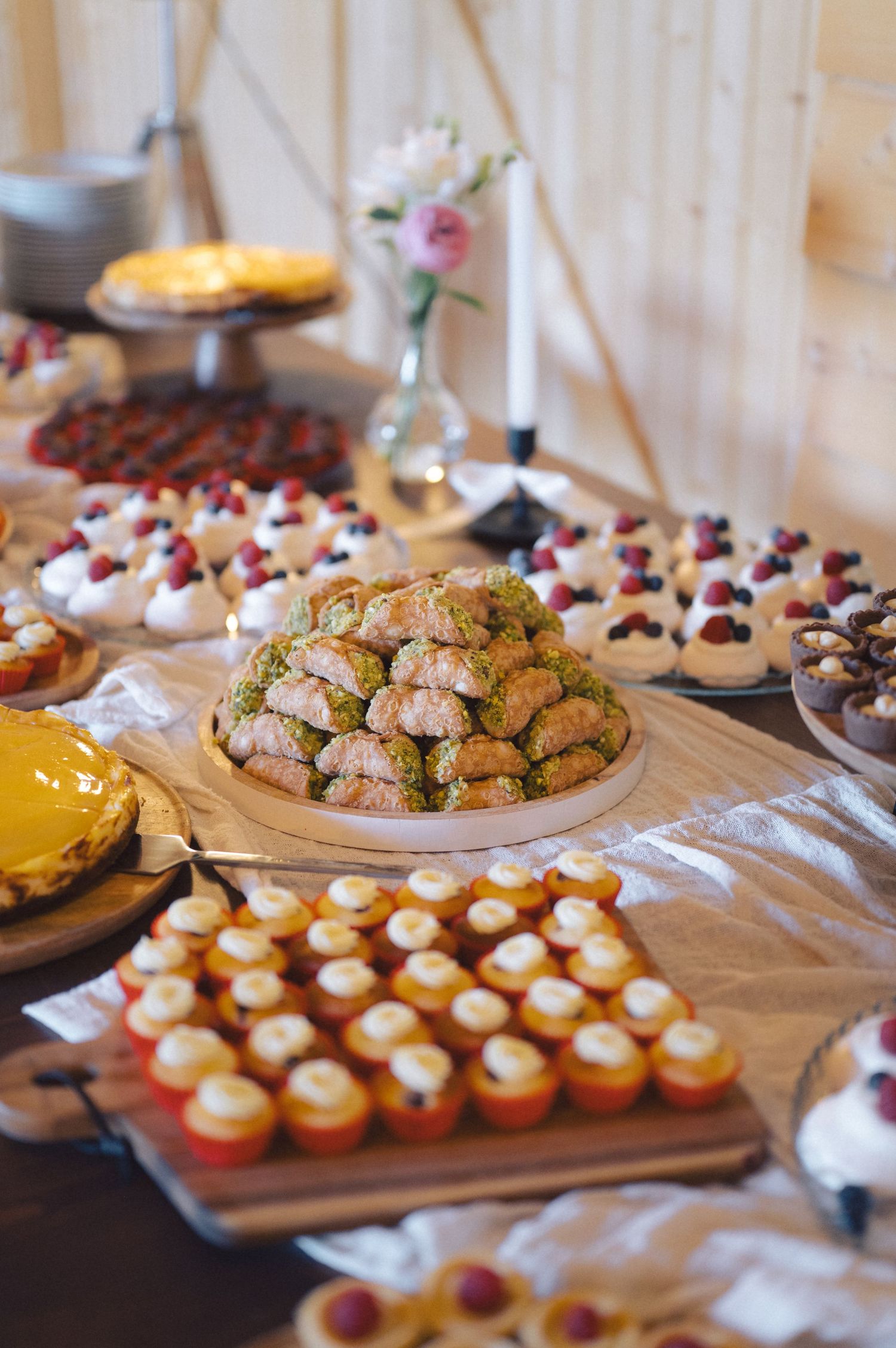 An elaborate dessert table featuring cookies, pastries and mini cupcakes displayed on various platters and cake stands.