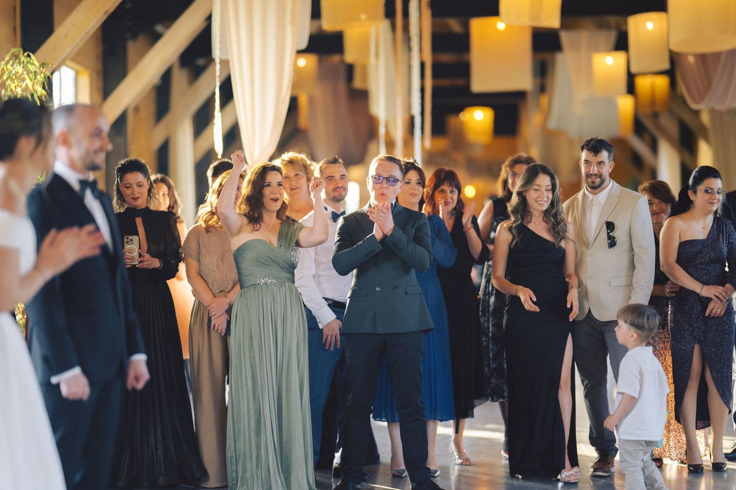 Wedding guests watching the ceremony in an indoor venue with warm lighting and rustic decor.
