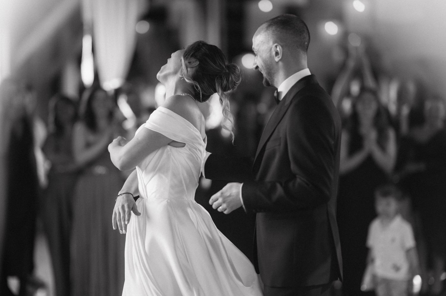 A romantic black and white photograph of a couple sharing their first dance at a wedding reception.