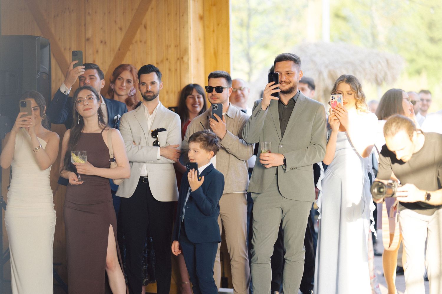 Wedding guests in formal attire react emotionally while watching a special moment at an indoor ceremony venue.
