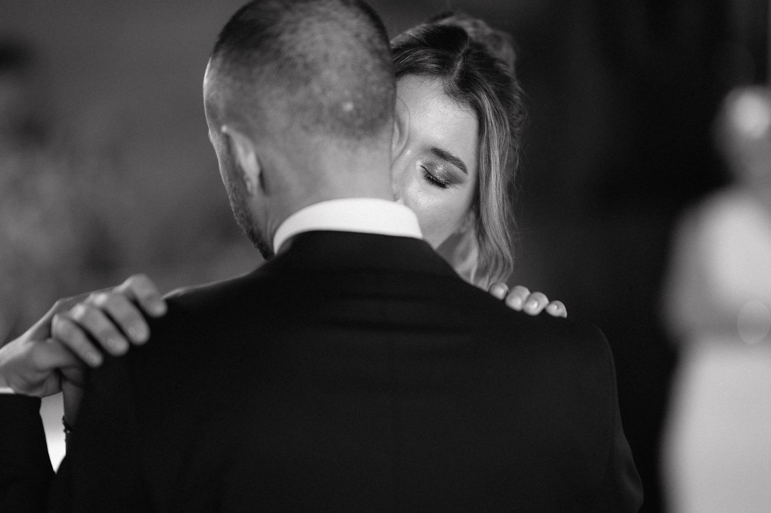 A tender black and white photograph captures an intimate dance embrace at a wedding reception.