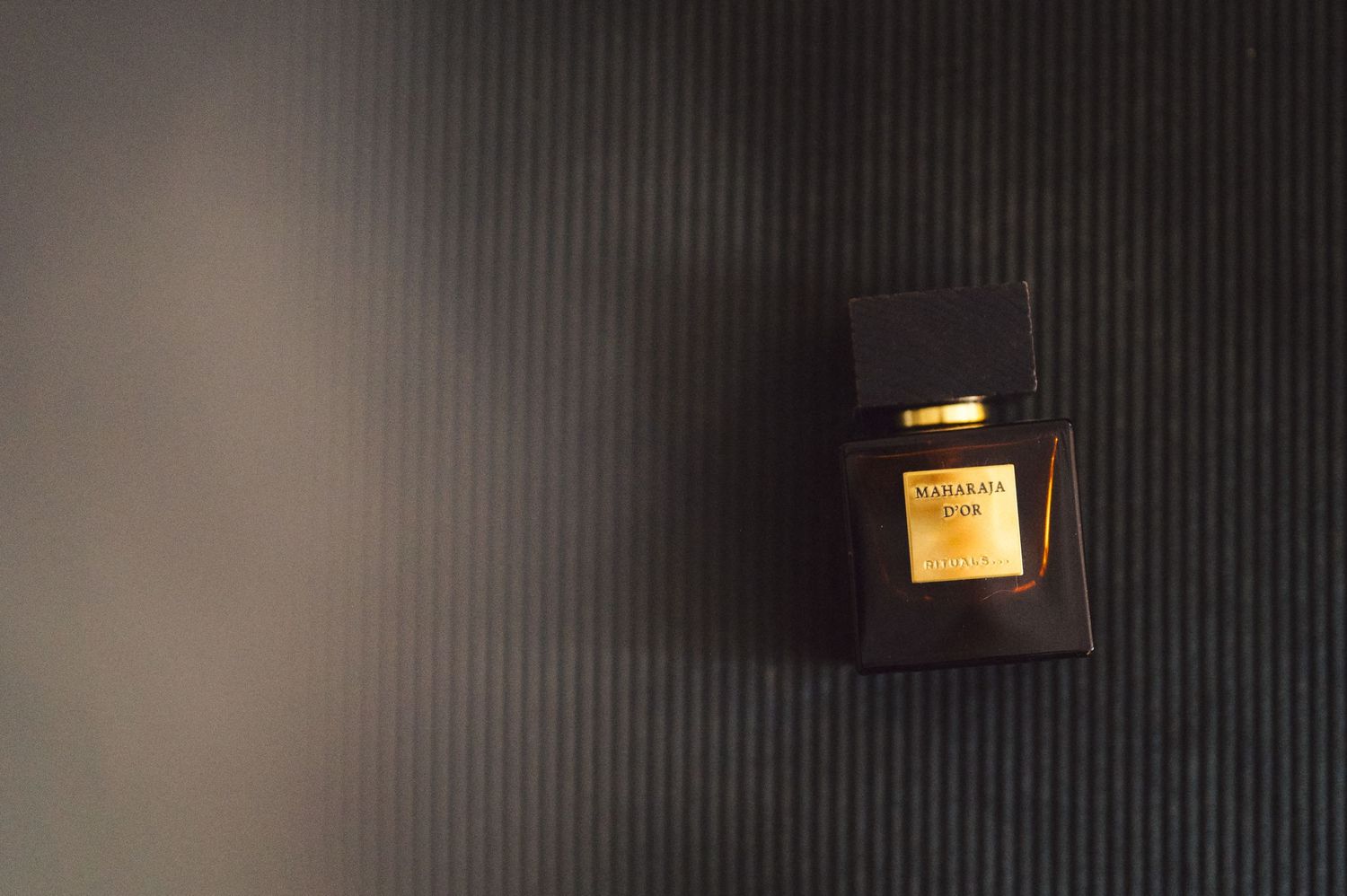A dark brown leather wallet illuminated by warm light against a textured black surface.