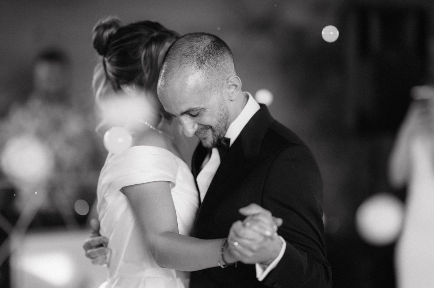 A romantic black and white image of a couple sharing an intimate dance moment at their wedding reception.