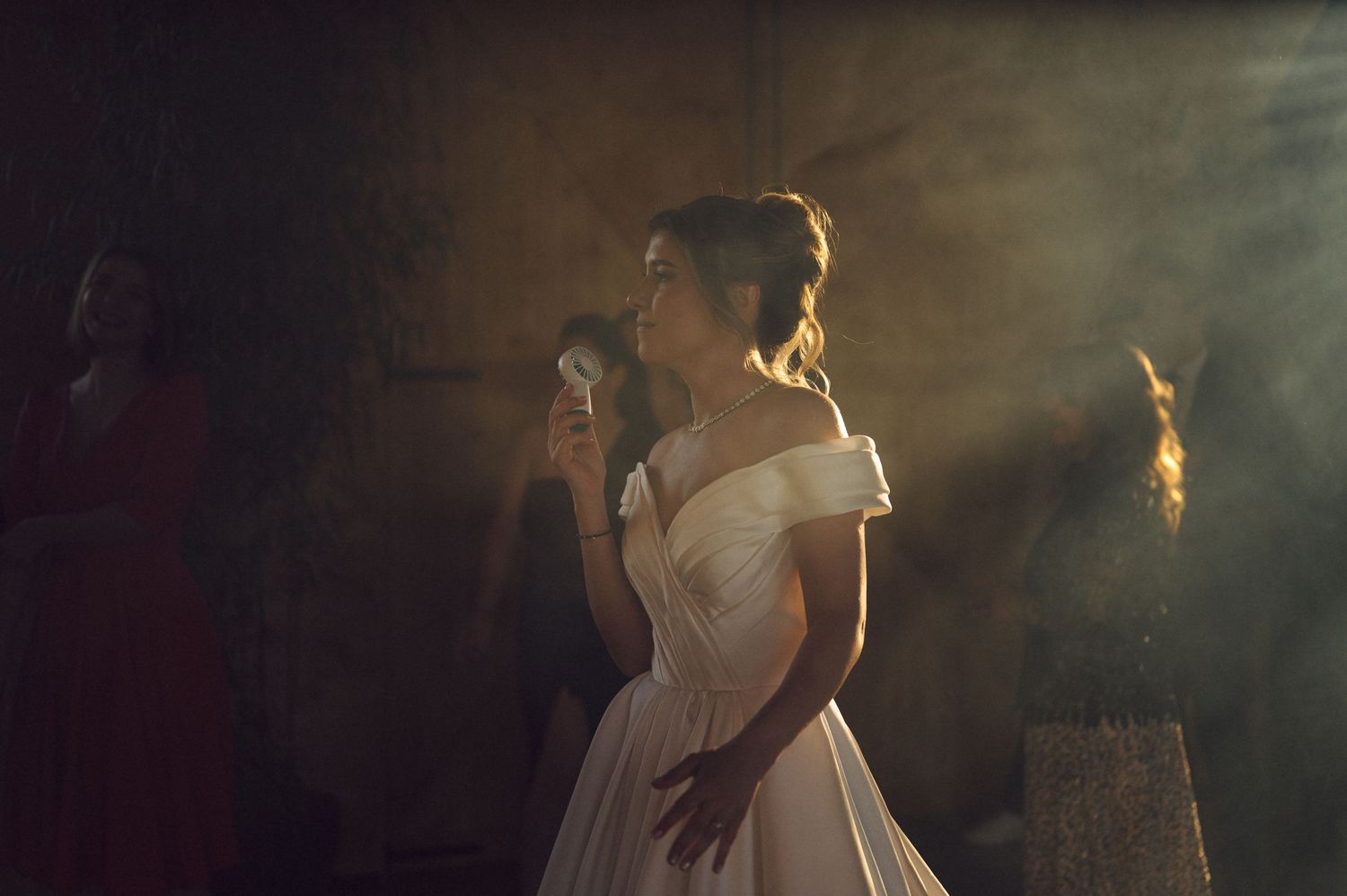 A figure in a flowing white off-shoulder gown stands gracefully in atmospheric stage lighting and theatrical haze.