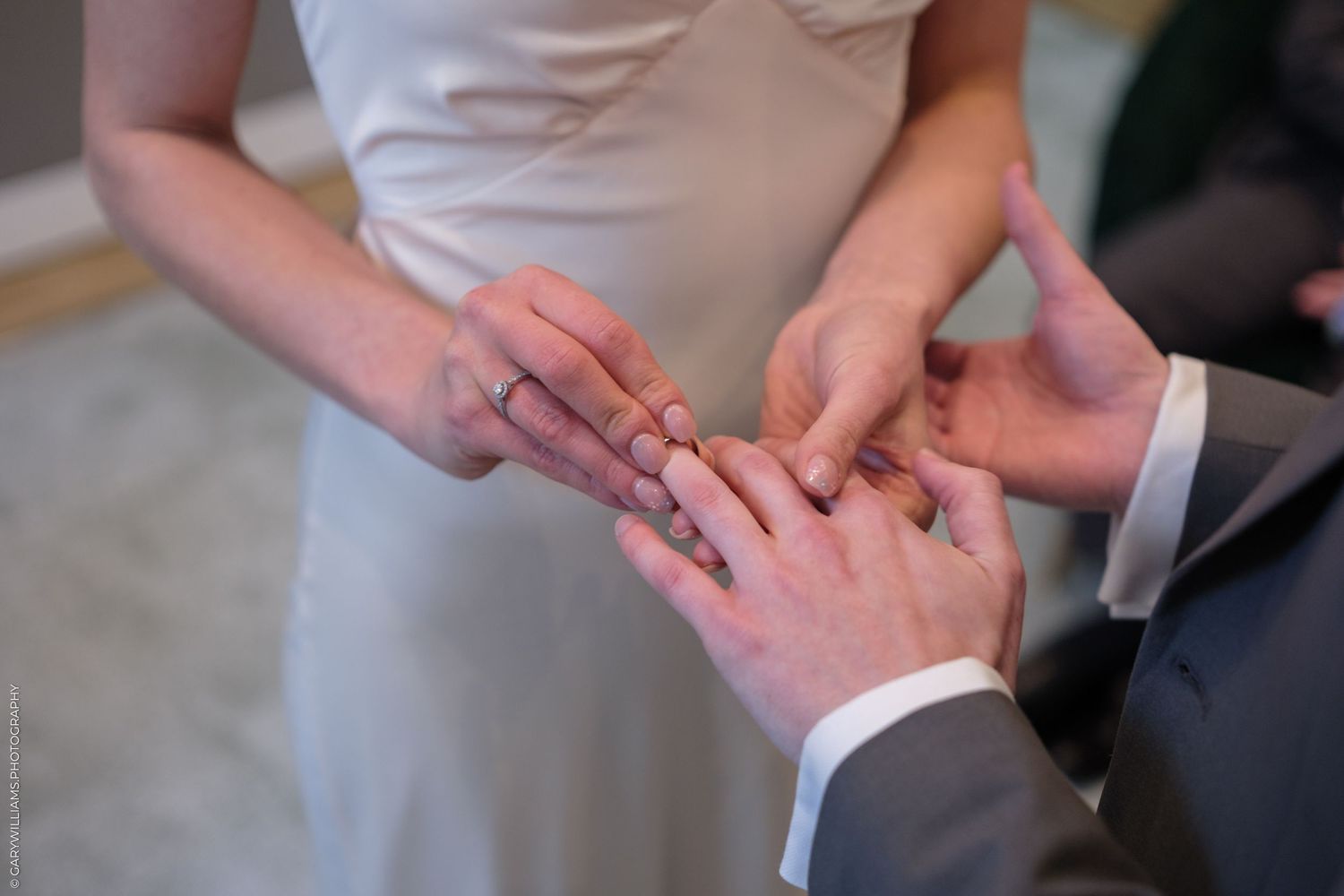 Close-up shot of hands exchanging wedding rings during a marriage ceremony.