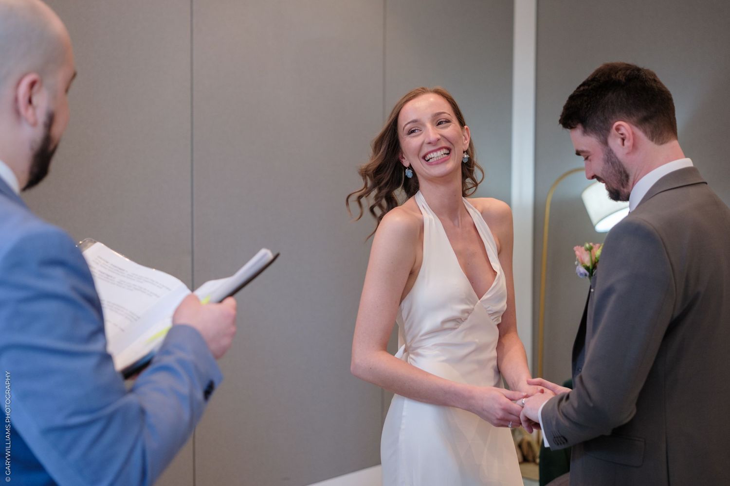 A wedding ceremony taking place indoors with a person in a white dress and others in formal attire.
