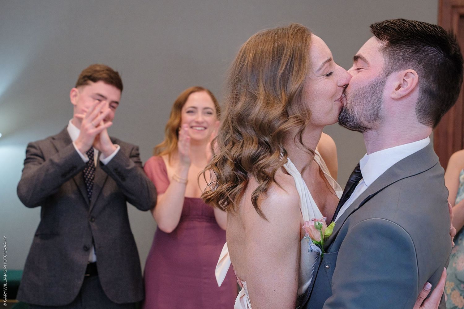 Wedding guests react with joy and applause as a couple shares their first kiss during an emotional ceremony.