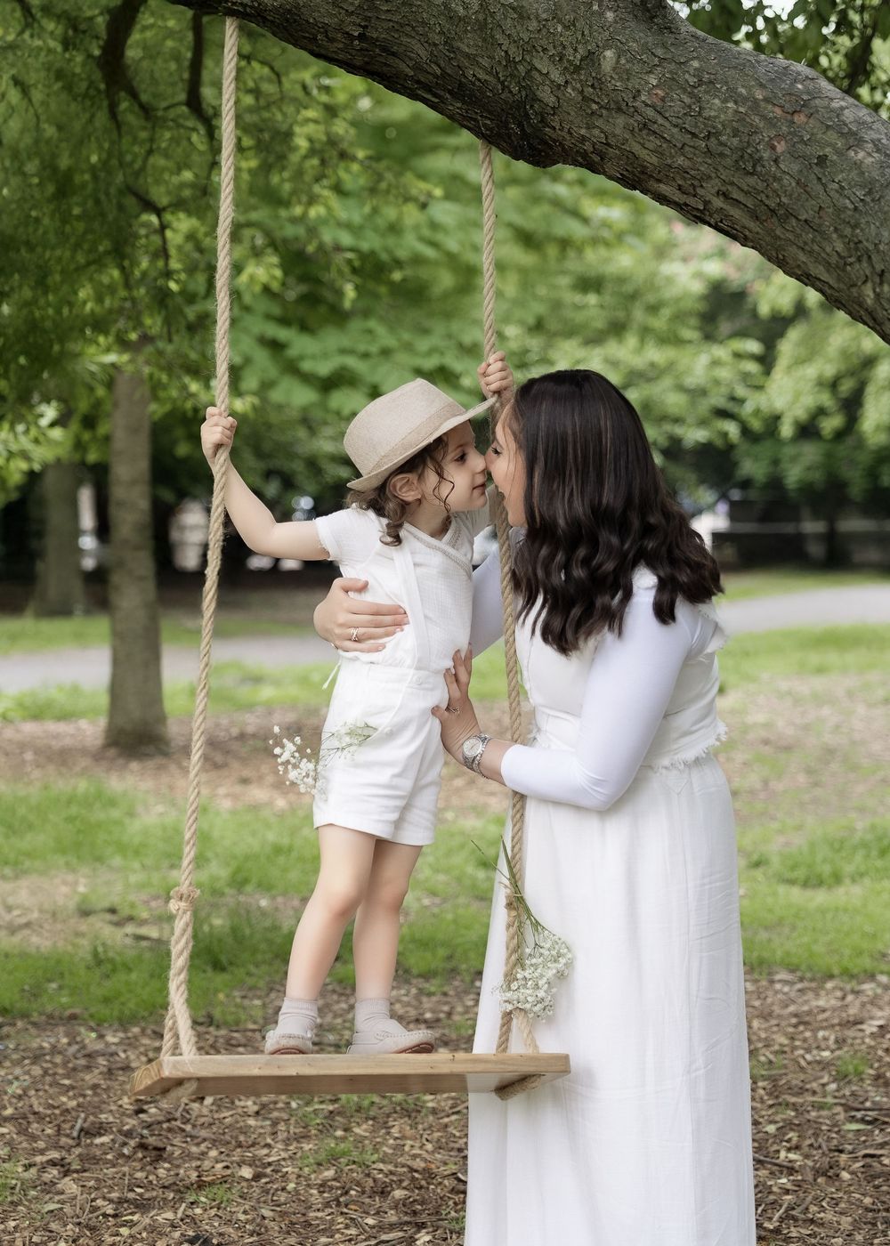 A series of candid family photos taken near a tree swing in a lush green park setting.