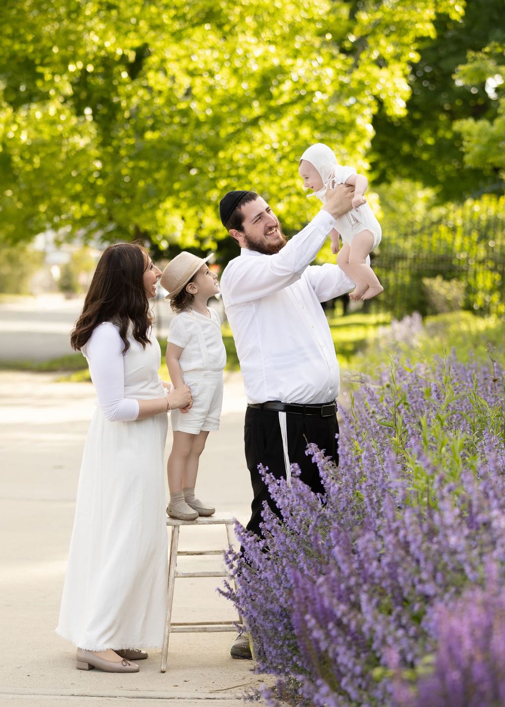 A couple in white clothing poses for dynamic dance portraits against a backdrop of vibrant purple lavender flowers.