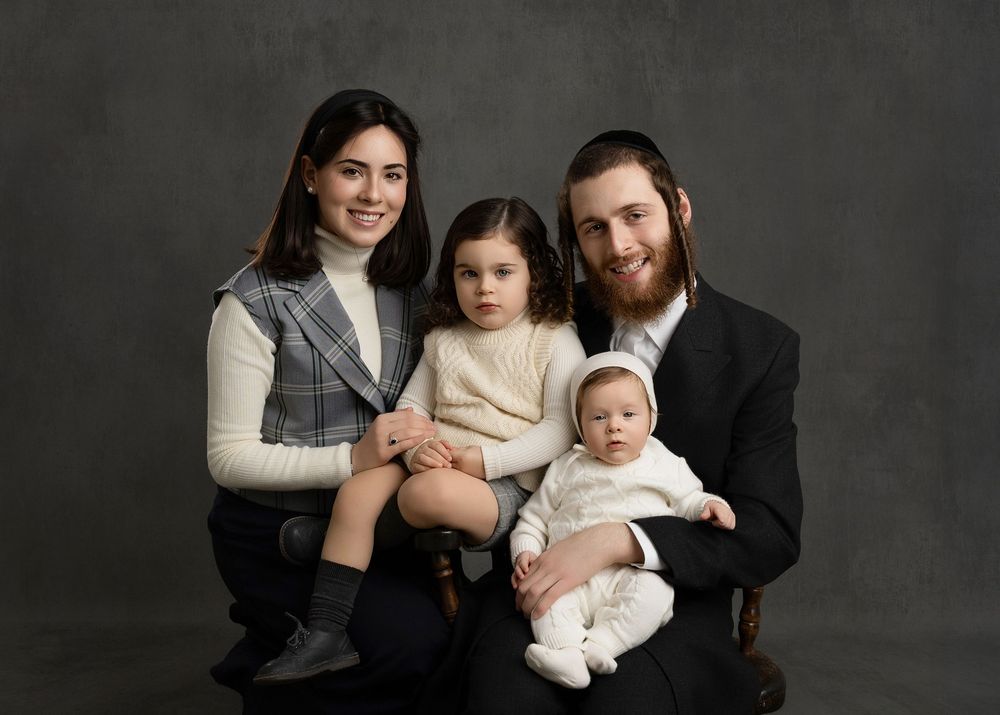 Professional studio portrait session showing family group in coordinated black and white outfits against dark background.
