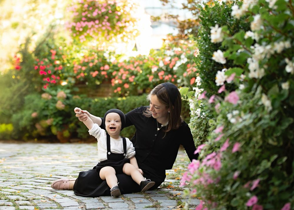 Garden photography session with people lounging on stone pathway amid blooming flowers.