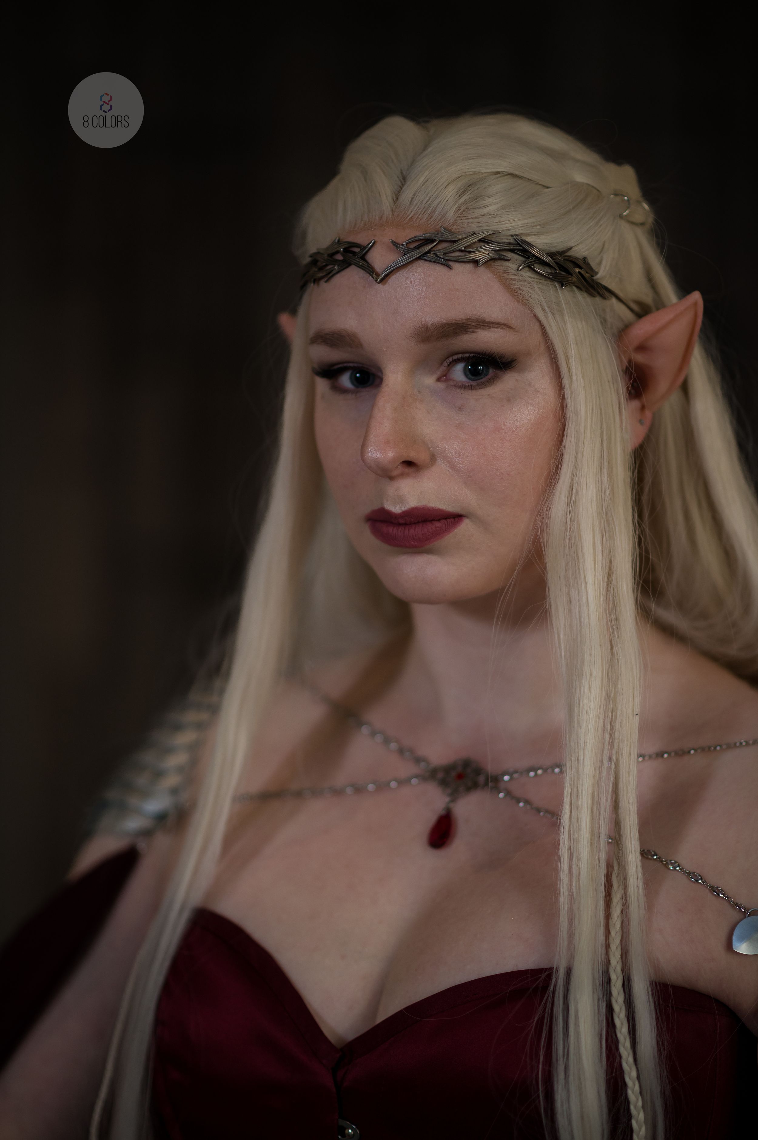 Fantasy elf cosplay featuring long platinum blonde hair, delicate crown, pointed ears and burgundy dress details.