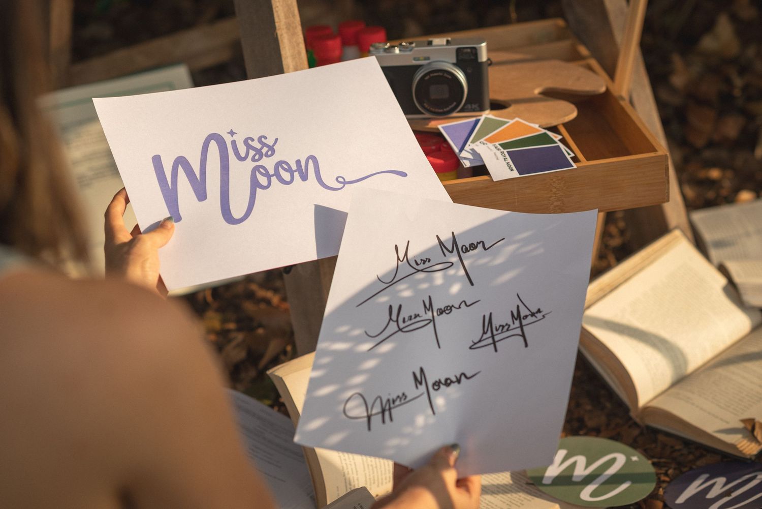 Handwritten note cards with Miss Mom text and signatures are displayed next to a vintage camera on a wooden surface.
