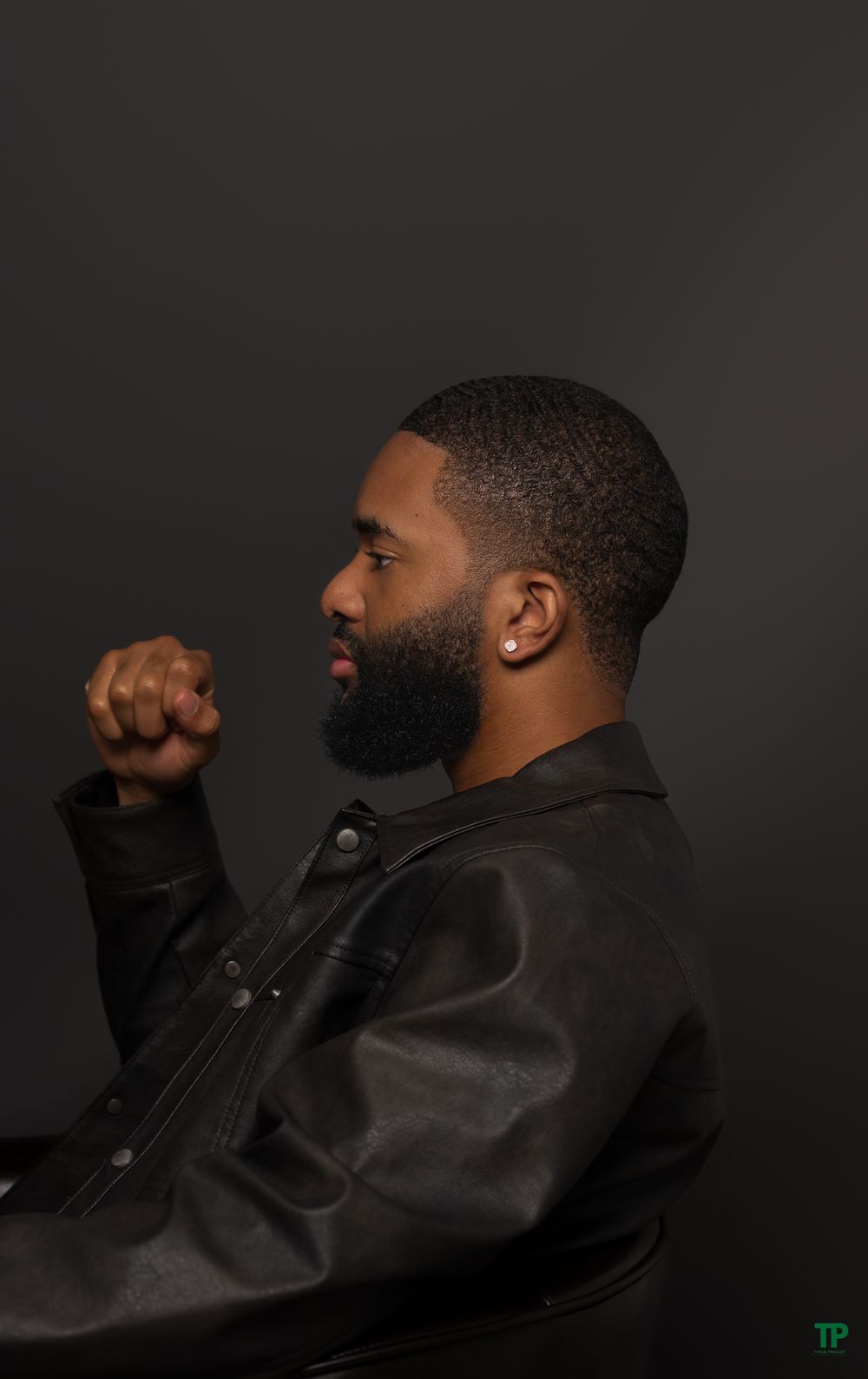 A profile portrait shows a person in a black jacket with a well-groomed beard against a dark background.