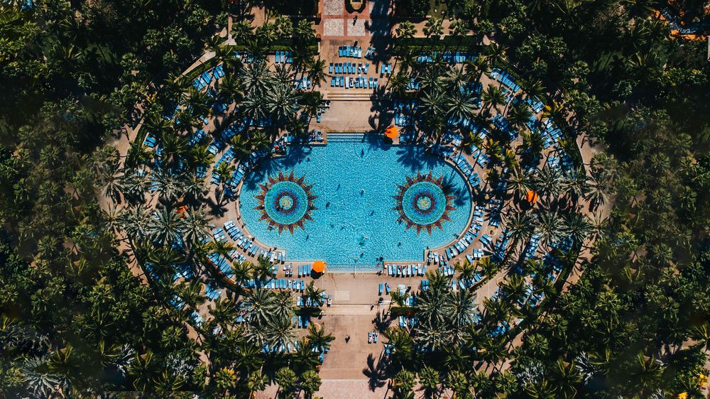 Aerial panorama of a luxury resort surrounded by lush tropical gardens and swimming pools.