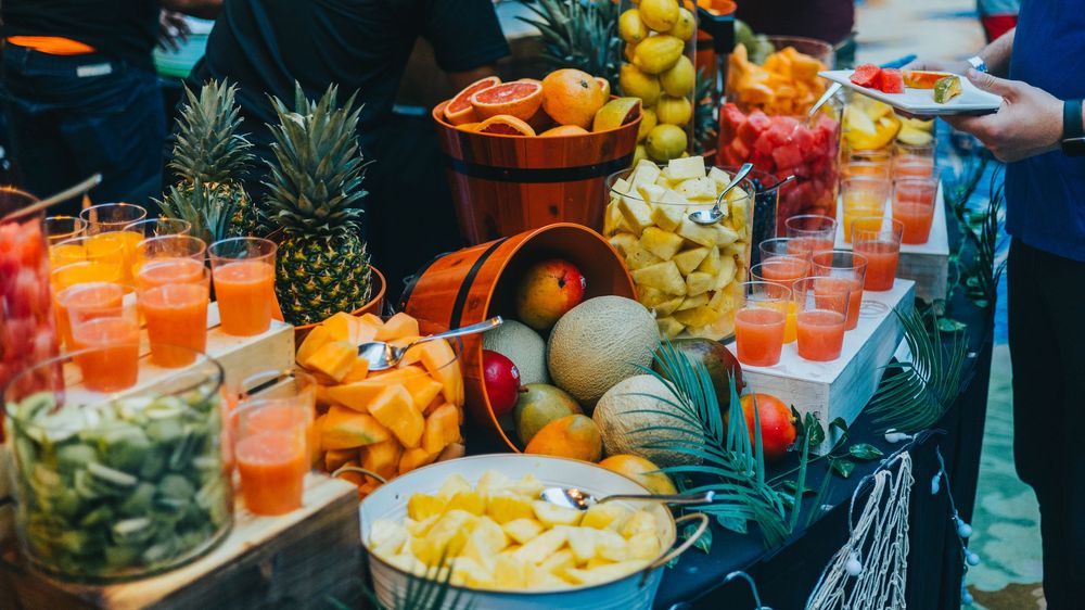 Colorful buffet spread of tropical fruits and beverages with pineapples and orange drinks.