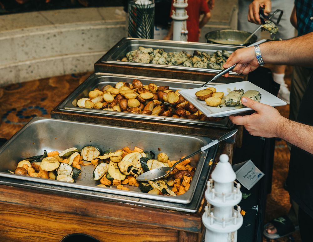 Long buffet table filled with roasted potatoes and various hot dishes.
