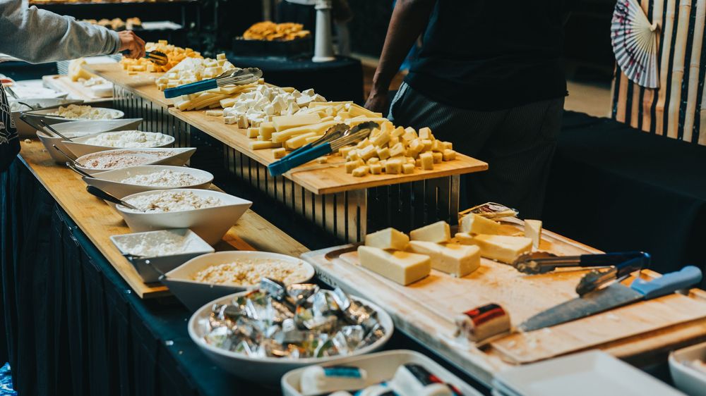 Panoramic view of catering buffet with various dishes laid out on wooden serving boards.