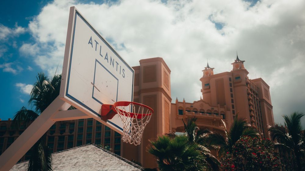 Basketball hoop against blue sky with Atlantis resort towers in background.