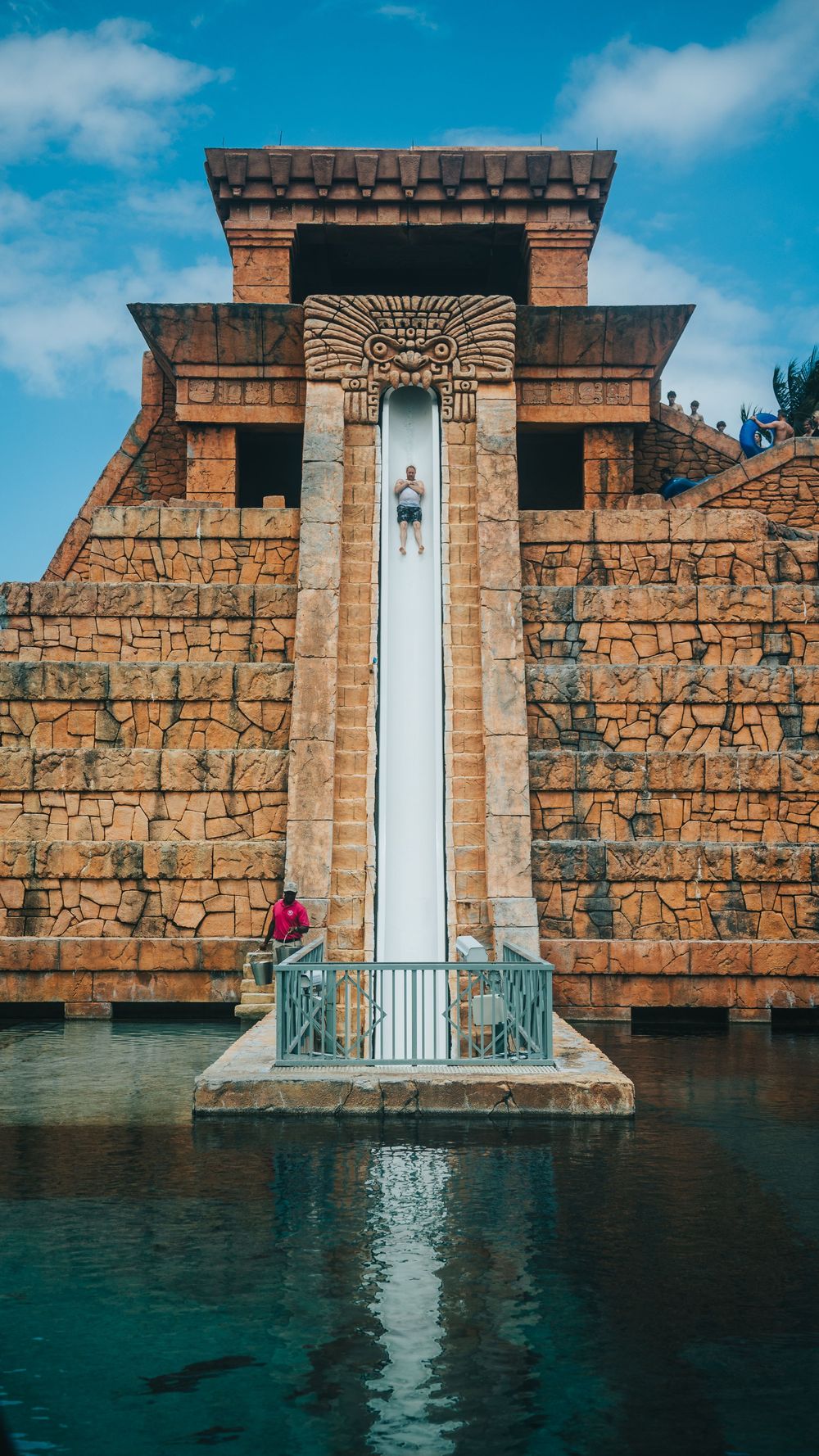 Water slide tower at Atlantis resort featuring Mayan-inspired architecture and turquoise pool.