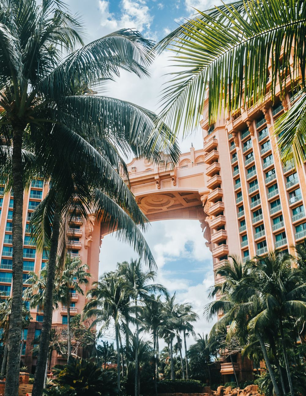 Pink towers of Atlantis resort framed by palm trees with decorative archway in center.